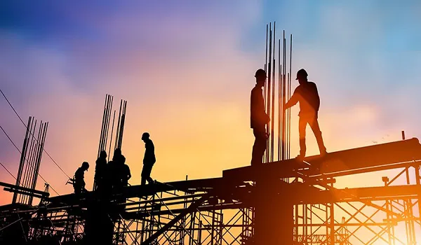 Silhouettes of construction workers on a steel structure at sunset